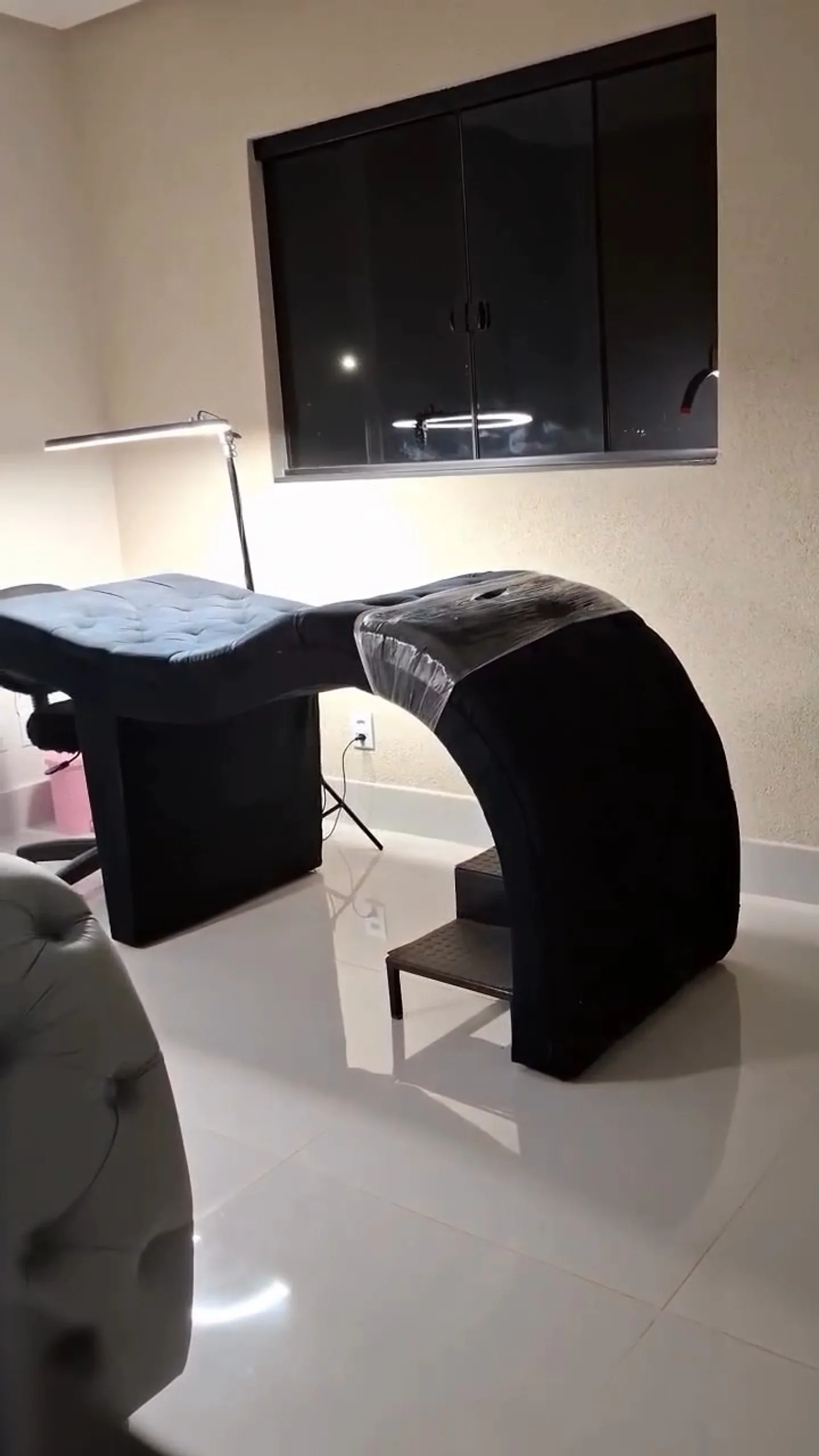 Sala de atendimento com duas macas de veludo preto e luminárias em arco