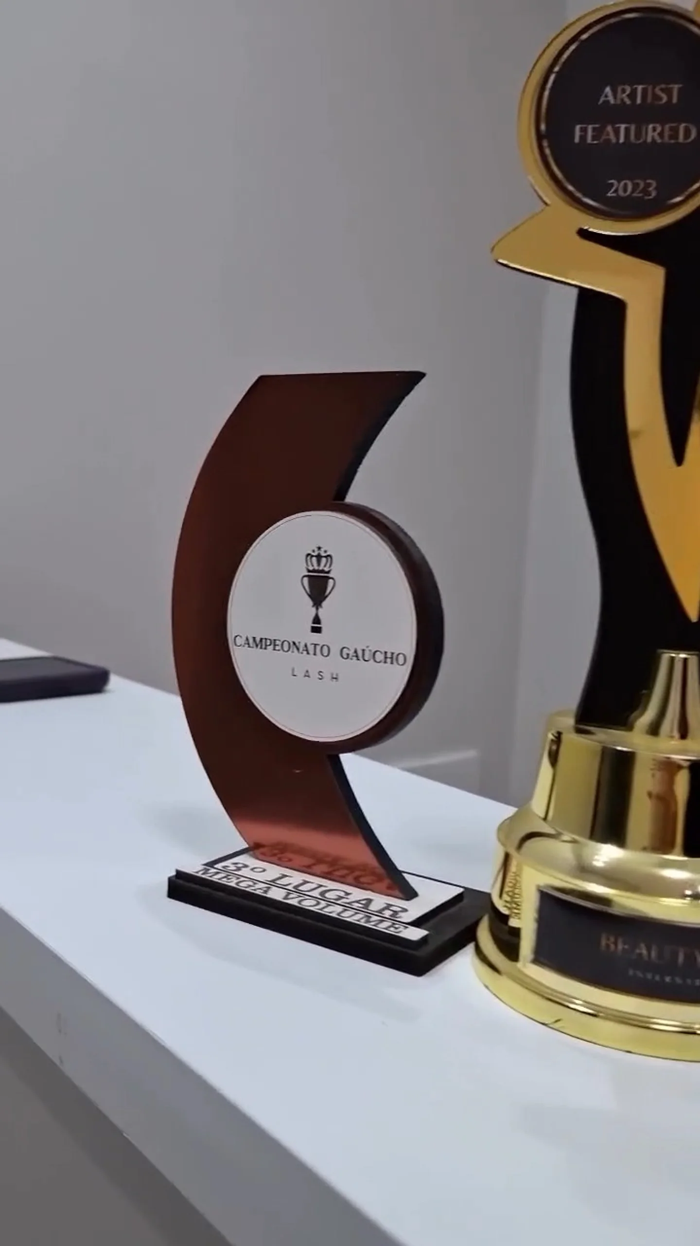 Troféu do Campeonato Gaúcho Lash, 3º lugar em Mega Volume, ao lado do troféu Artist Featured 2023